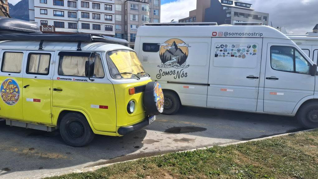 dois veículos: uma Kombi amarela antiga e uma Mercedes Sprinter. As duas são casas rodantes