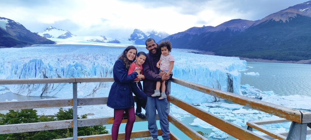 uma família: pai, mãe e um casal de filhos ante uma pasarela do glaciar Perito Moreno