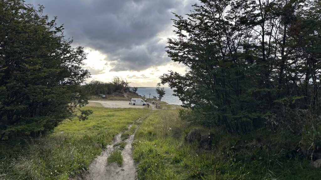 uma paisagem de mata com um motohome em frente a um lago de fundo.