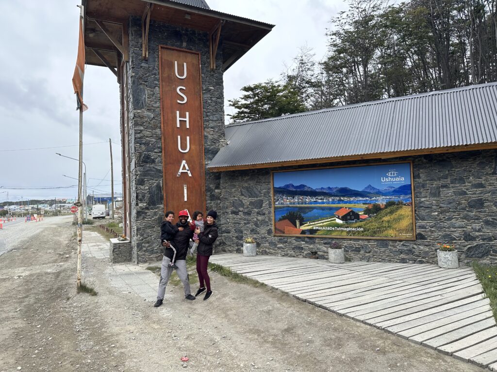 uma família feliz no portal de entrada da cidade de Ushuaia