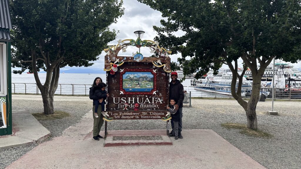 família em frente a plada de fim do mundo em Ushuaia